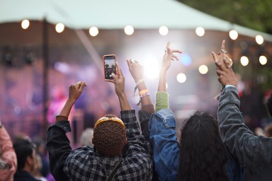 Young man photographing through smart phone with friends at music festival