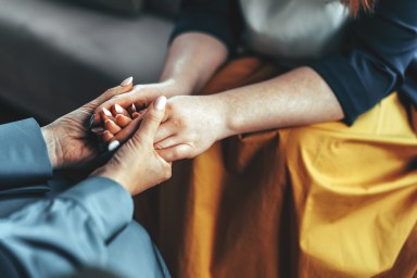 Two women sitting in armchairs and talking. Woman psychologist talking to patient woman. Coach giving hands to smiling woman. Therapist's gestures. Female talking in coworking office