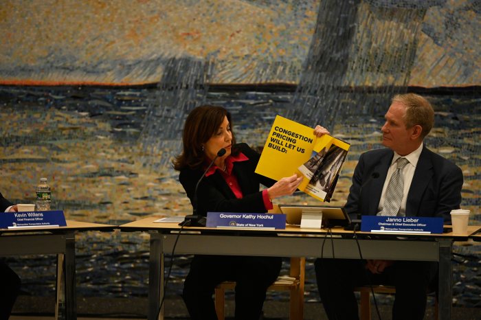 a woman holds up a book at a table showing info about congetion pricing