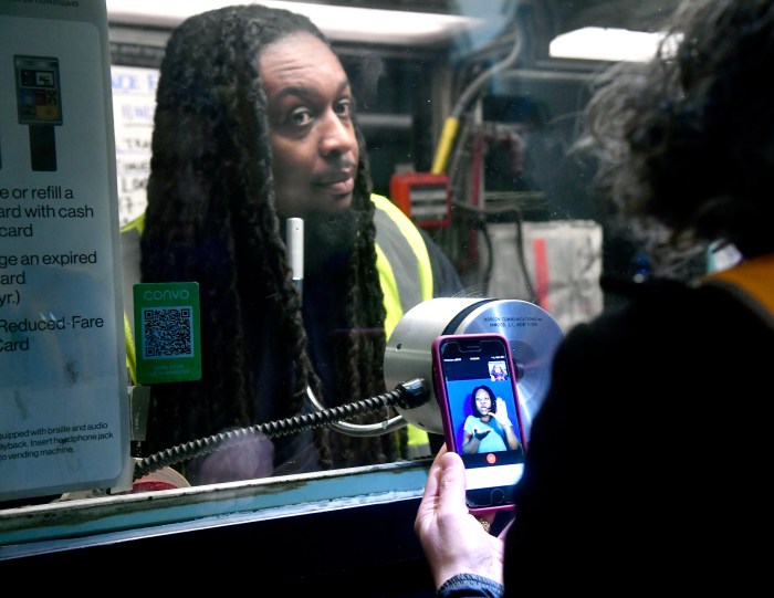 NYC subway station agent with customer holding a phone