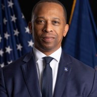 man in a suit in front of American flag