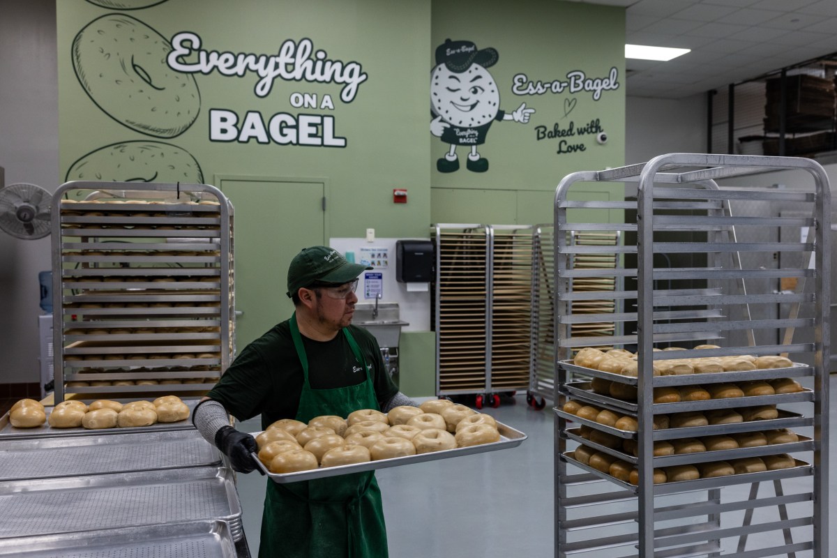 an employee stands with a tray of bagels at the ess-a-bagel factory