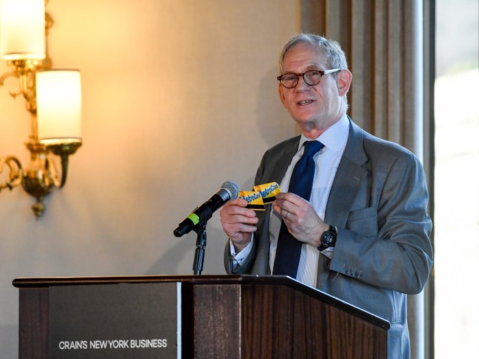 man at a podium holding MetroCards