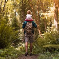 Father and daughter walking through the forest.