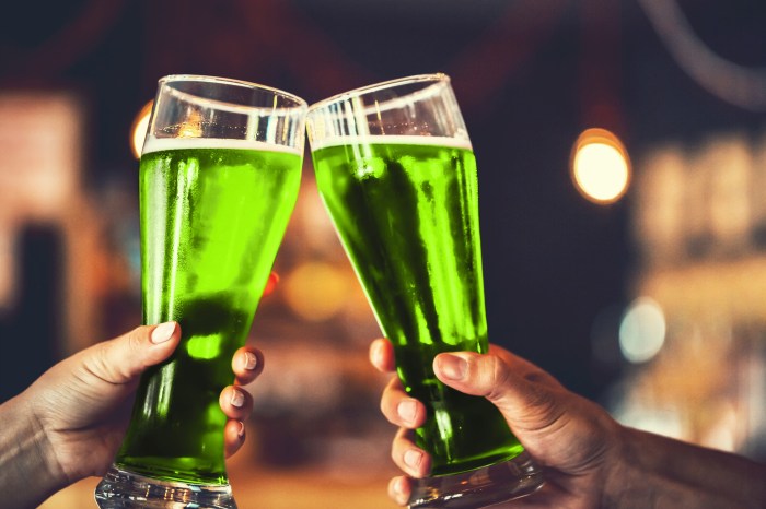 Two friends toasting with glasses of green beer at the pub with free space for your text. Beautiful background of the Beer Fest and St. Patrick's day. fine grain. Soft focus. Shallow DOF