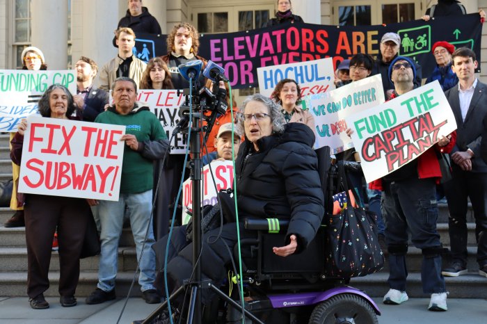 people outside on steps holding signs to support funding for NYC subway and transit improvements