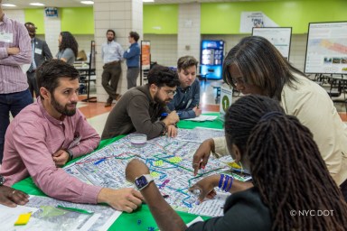 people sitting at a table looking at papers regarding the Cross Bronx Expressway