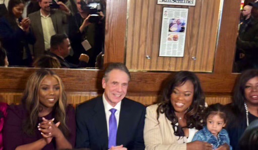 Andrew Cuomo sitting at a table with supporters