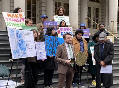 group of people on outside stairs advocating for Fair Fares transit discount program in NYC