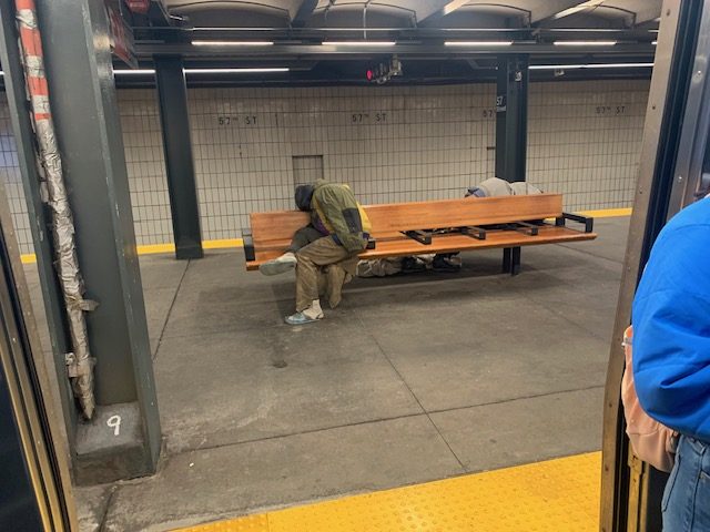 people who are homeless on NYC trains sitting on a bench in a subway station