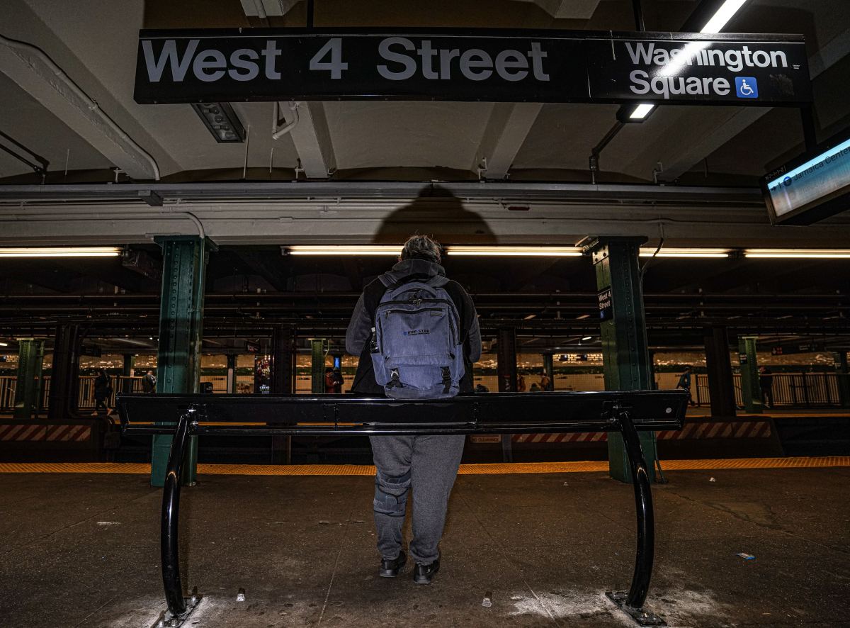 West 4th Street subway station with people leaning on metal bars